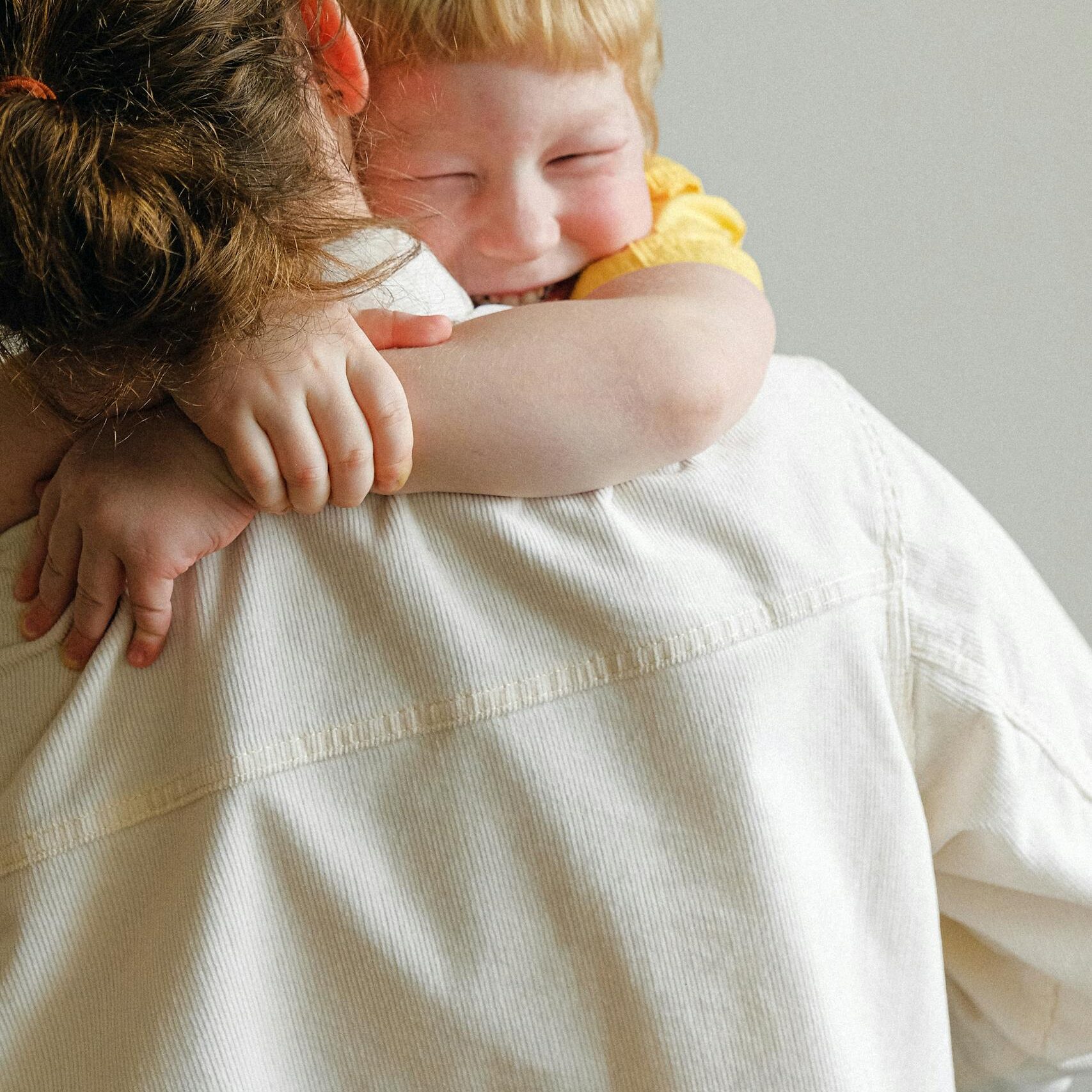 A joyful child embraces their mother in a warm, loving hug, capturing family affection.
